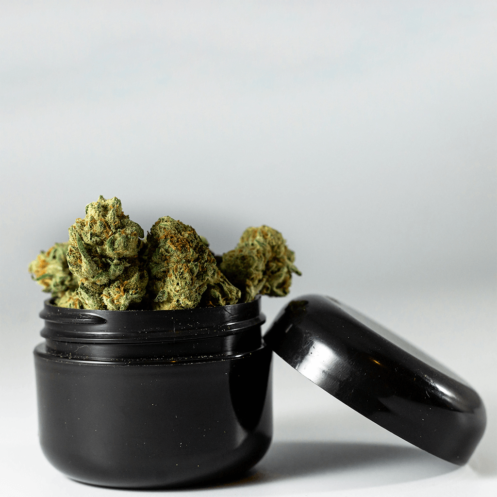 Cannabis flower overflowing small black jar